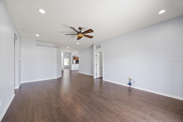 unfurnished living room featuring a ceiling fan, visible vents, baseboards, arched walkways, and dark wood-style floors