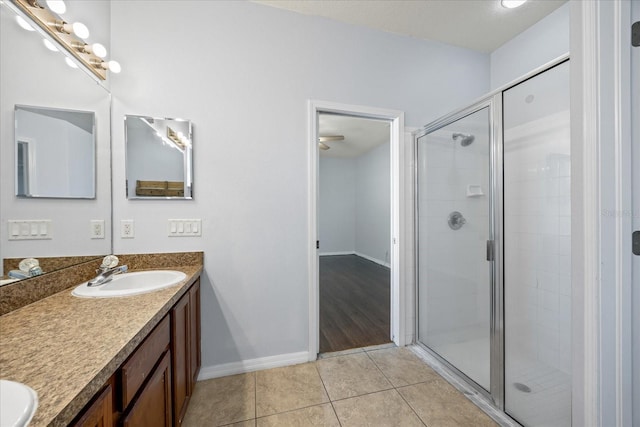 bathroom with a stall shower, tile patterned flooring, vanity, and baseboards