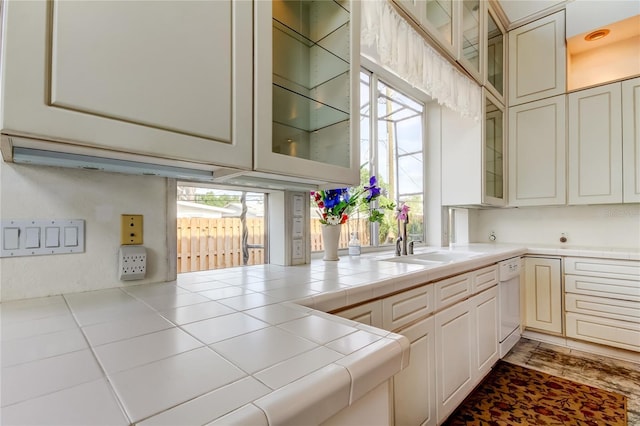 919 Sandpiper Way S, Saint Petersburg, FL 33707 - kitchen featuring dishwasher, glass insert cabinets, tile counters, and a sink