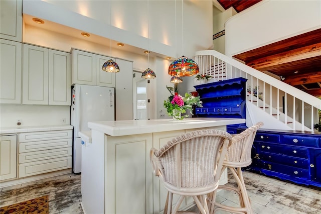 919 Sandpiper Way S, Saint Petersburg, FL 33707 - kitchen with freestanding refrigerator, hanging light fixtures, a kitchen island, tile counters, and a high ceiling