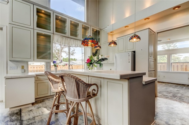 919 Sandpiper Way S, Saint Petersburg, FL 33707 - kitchen with freestanding refrigerator, tile counters, a center island, and a kitchen bar