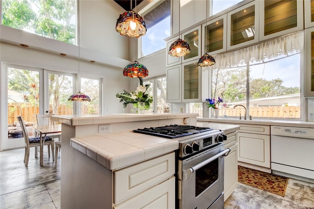 919 Sandpiper Way S, Saint Petersburg, FL 33707 - kitchen with white dishwasher, tile countertops, a healthy amount of sunlight, a sink, and gas range