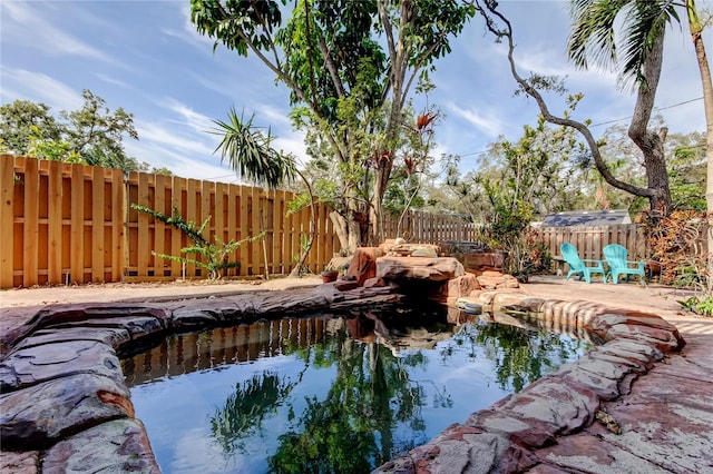 919 Sandpiper Way S, Saint Petersburg, FL 33707 - view of swimming pool with a small pond and a fenced backyard