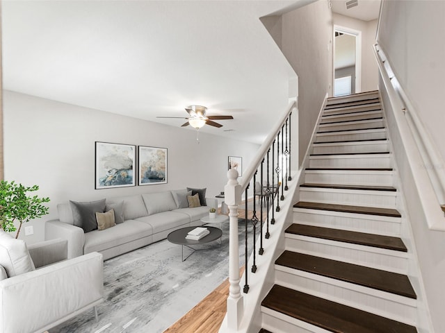 stairway with a ceiling fan and wood finished floors