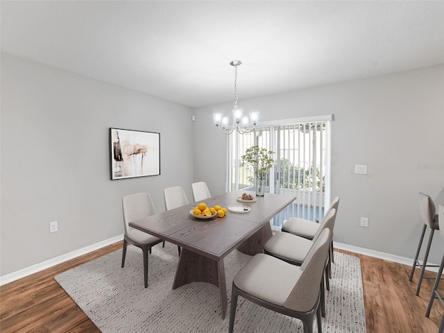 dining space with baseboards, wood finished floors, and a chandelier