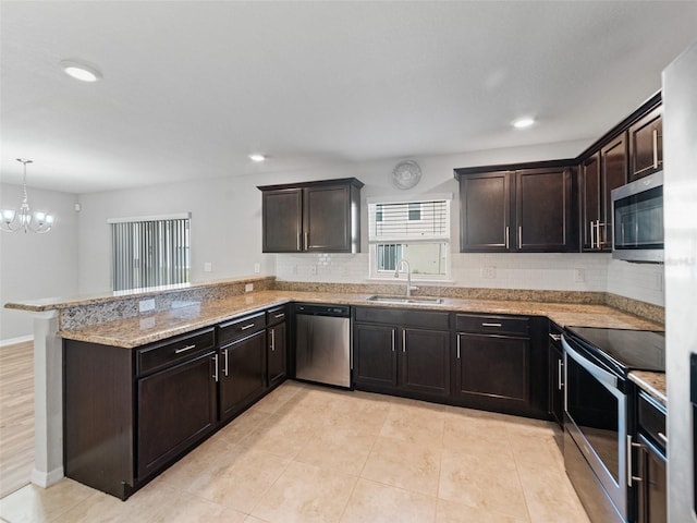 kitchen featuring decorative backsplash, a peninsula, light stone countertops, a sink, and stainless steel appliances