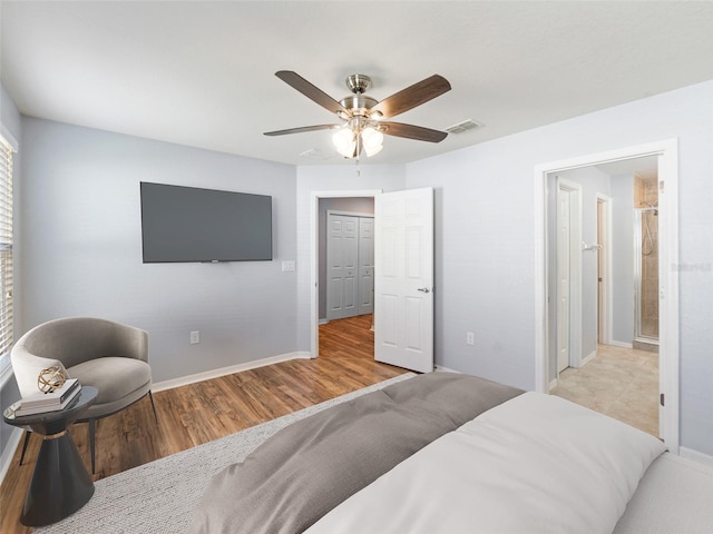 bedroom featuring a ceiling fan, baseboards, visible vents, and wood finished floors