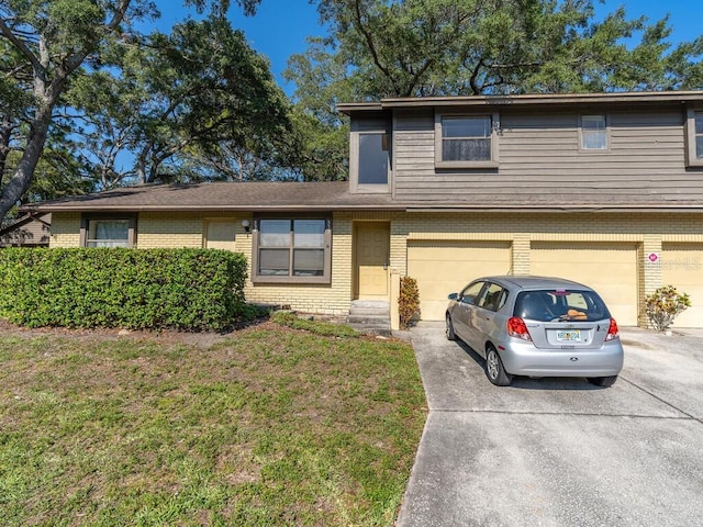 view of front of property featuring driveway, brick siding, a garage, and a front yard