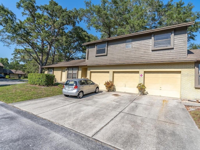 view of front facade with driveway, brick siding, an attached garage, and a front yard