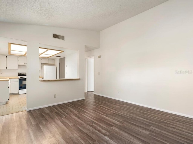 unfurnished living room with a textured ceiling, visible vents, baseboards, vaulted ceiling, and dark wood-style floors