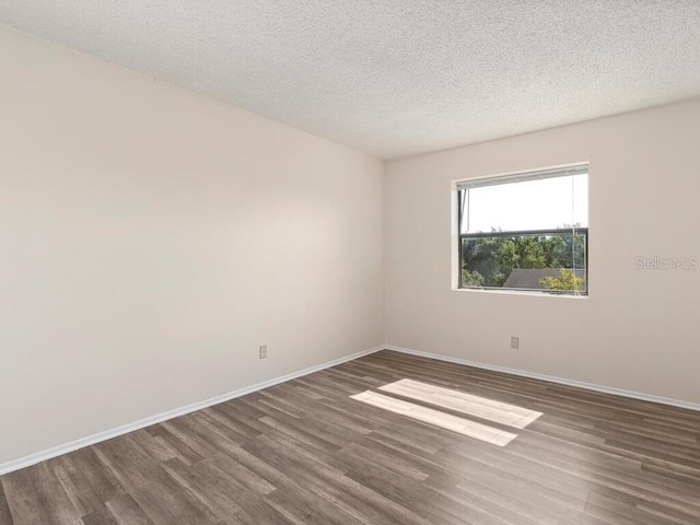 spare room with baseboards, a textured ceiling, and wood finished floors