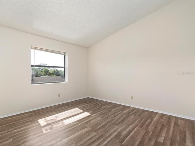 spare room with a textured ceiling, baseboards, and wood finished floors