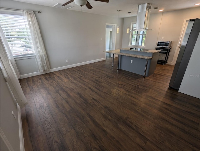 kitchen featuring island range hood, black electric cooktop, a kitchen island, a kitchen breakfast bar, and dark wood-type flooring