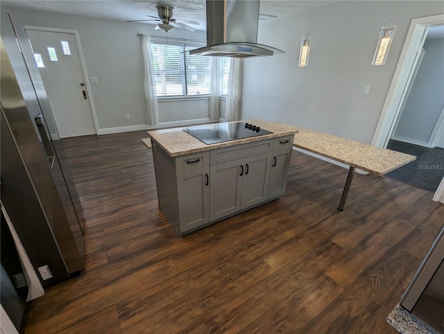 kitchen with island range hood, black electric cooktop, a ceiling fan, dark wood finished floors, and baseboards