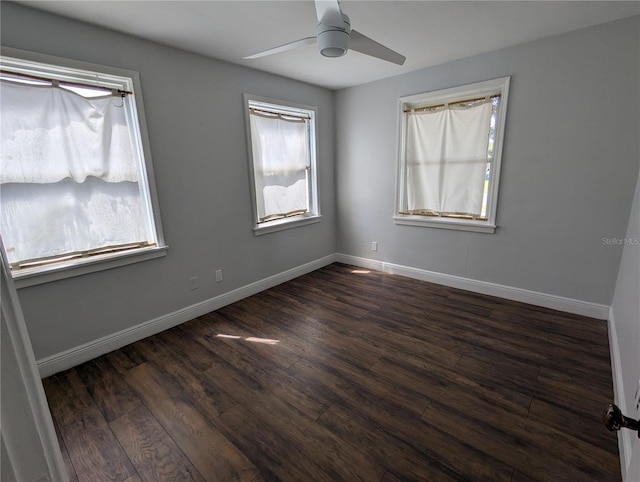 empty room with dark wood-style floors, a ceiling fan, and baseboards