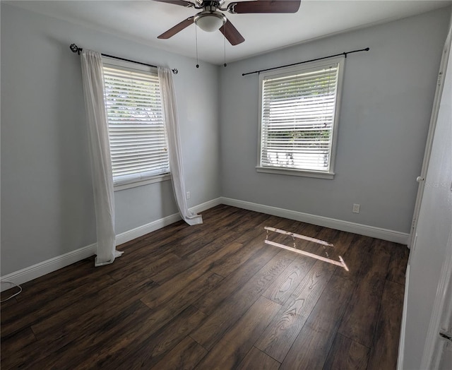 unfurnished room with healthy amount of natural light, dark wood-style floors, a ceiling fan, and baseboards