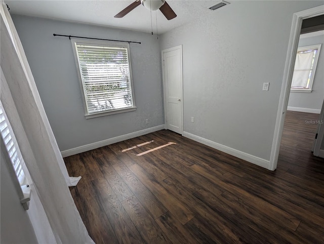 empty room with a ceiling fan, dark wood-style flooring, and baseboards