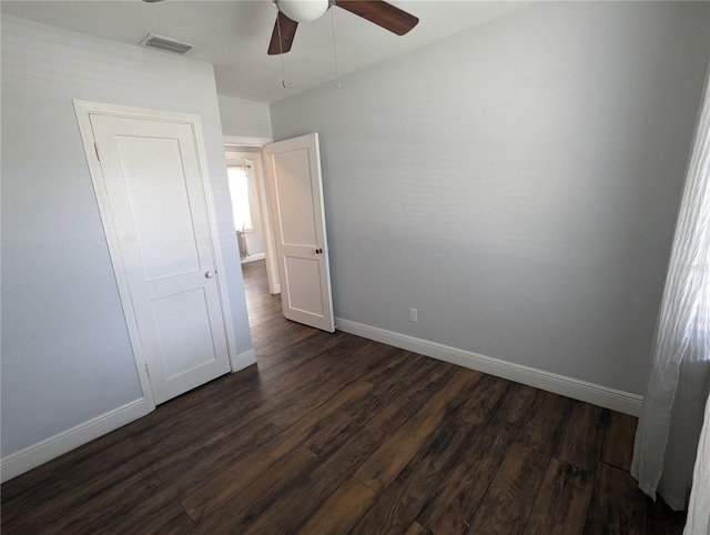 unfurnished bedroom with dark wood-style flooring, baseboards, and ceiling fan