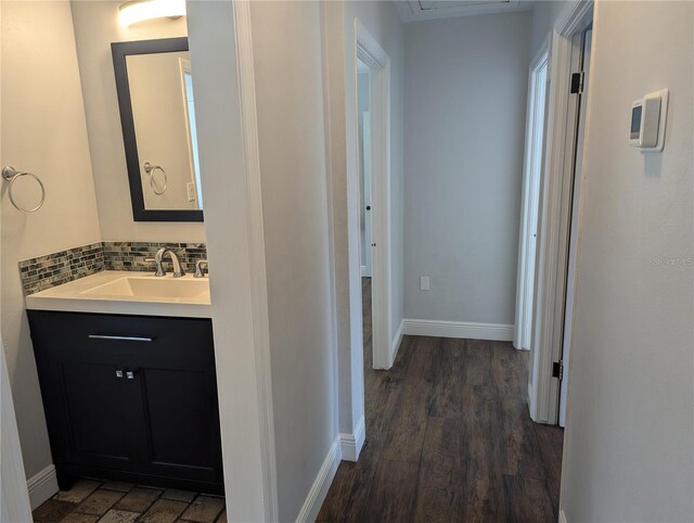 hallway with dark wood finished floors, baseboards, and a sink