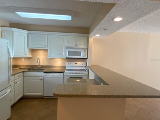 kitchen featuring white appliances, a sink, recessed lighting, dark tile patterned floors, and a textured ceiling