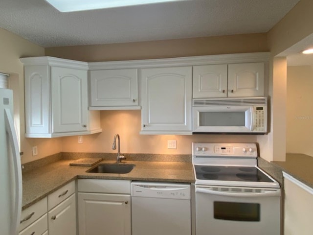 kitchen with white appliances, a sink, and white cabinets