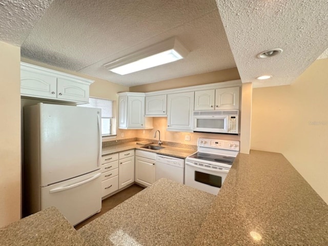 kitchen with white appliances, a sink, a textured ceiling, white cabinets, and recessed lighting