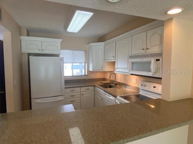 kitchen with white appliances, a sink, white cabinets, a peninsula, and recessed lighting