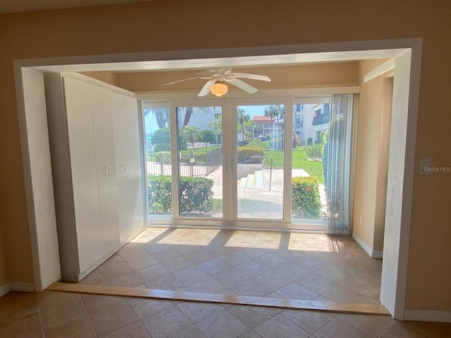 doorway to outside featuring a ceiling fan, inlaid floor details, baseboards, and tile patterned flooring