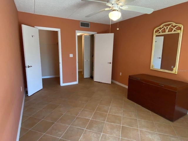 unfurnished bedroom featuring light tile patterned floors, ceiling fan, baseboards, and a textured ceiling