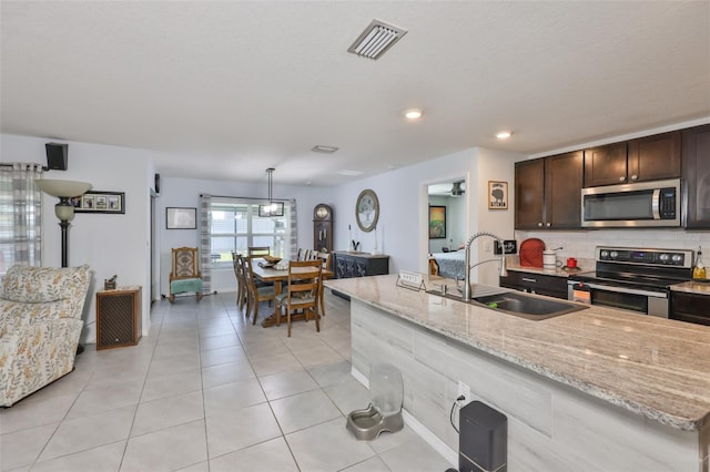kitchen with light stone countertops, dark brown cabinets, visible vents, a sink, and stainless steel appliances