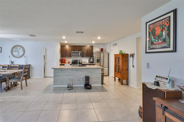 kitchen with light countertops, appliances with stainless steel finishes, dark brown cabinetry, and a sink
