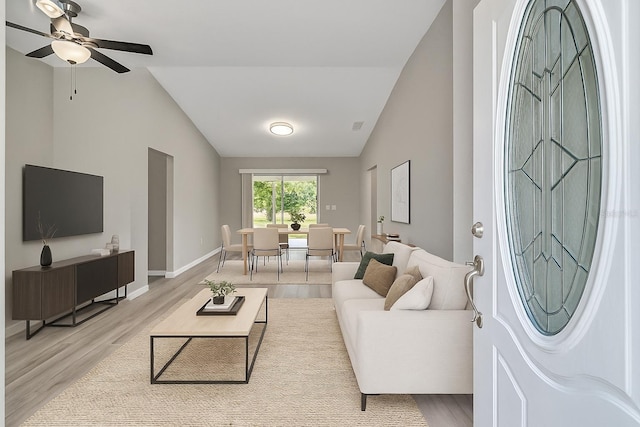 living room with vaulted ceiling, light wood-style flooring, a ceiling fan, and baseboards