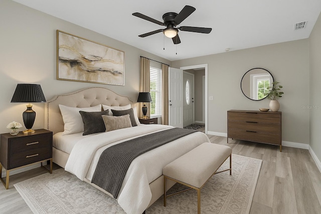bedroom featuring light wood-type flooring, multiple windows, baseboards, and a ceiling fan