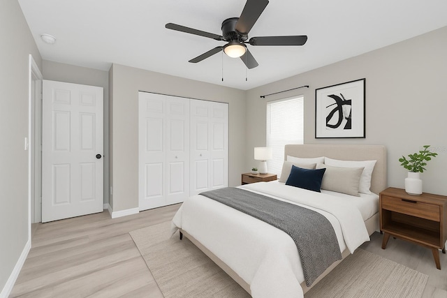 bedroom featuring a closet, light wood-style floors, baseboards, and ceiling fan