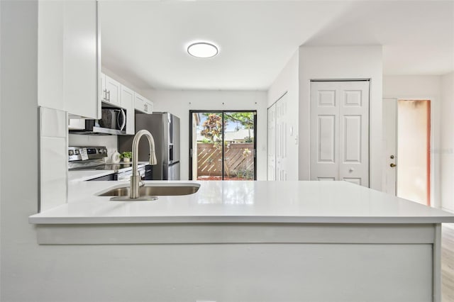 2953 Yucca Ct, Palm Harbor, FL 34684 - kitchen with stainless steel appliances, light countertops, a sink, a peninsula, and white cabinets