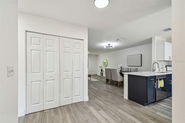 2953 Yucca Ct, Palm Harbor, FL 34684 - kitchen with dishwasher, a sink, blue cabinets, light wood-style floors, and light countertops