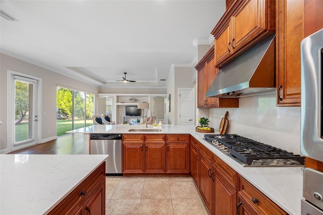 kitchen featuring brown cabinetry, a peninsula, appliances with stainless steel finishes, and a sink