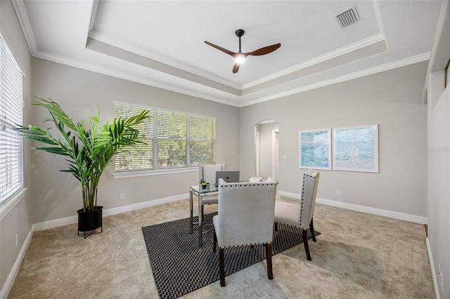 dining area with plenty of natural light, visible vents, a raised ceiling, arched walkways, and light colored carpet