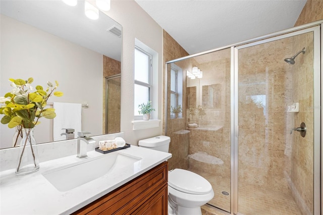 full bath with toilet, vanity, visible vents, and a shower stall