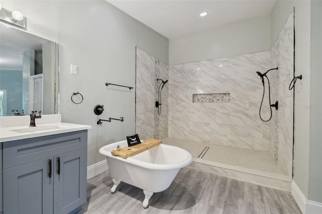 bathroom with vanity, a freestanding tub, wood finished floors, baseboards, and a tile shower