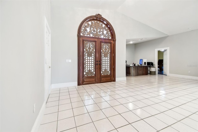 entryway with light tile patterned floors, baseboards, and vaulted ceiling