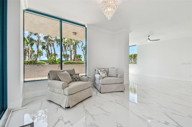 living area with baseboards, marble finish floor, crown molding, and ceiling fan with notable chandelier