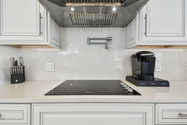 kitchen featuring decorative backsplash, white cabinetry, black electric stovetop, and custom range hood