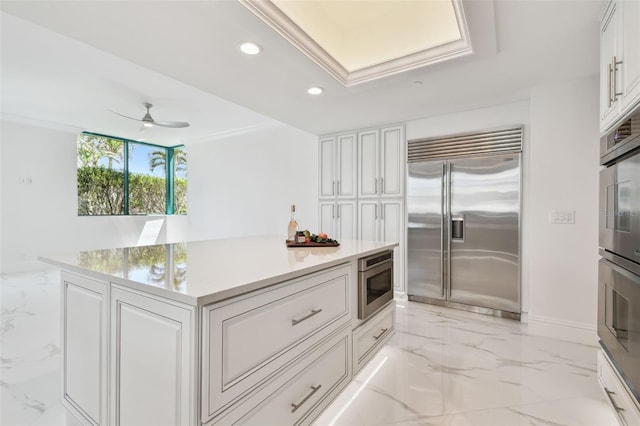 kitchen featuring recessed lighting, marble finish floor, built in appliances, and white cabinetry