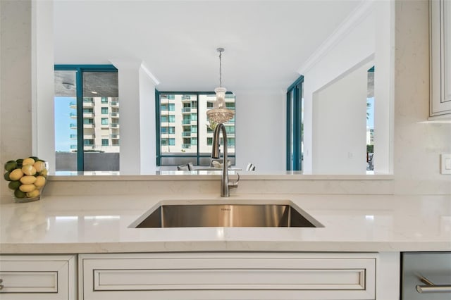kitchen with light stone counters, a sink, a healthy amount of sunlight, and decorative light fixtures
