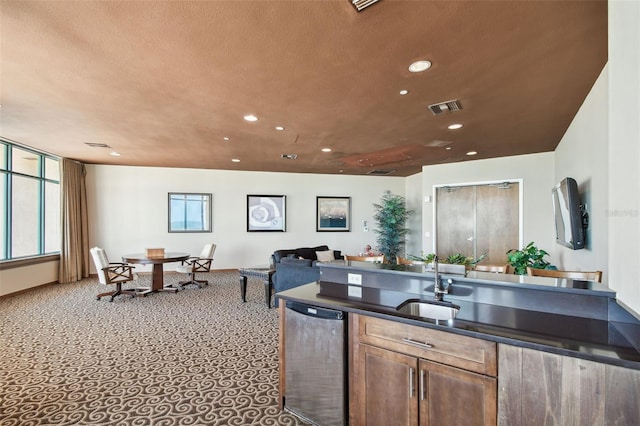 kitchen featuring dark countertops, a sink, carpet, recessed lighting, and visible vents