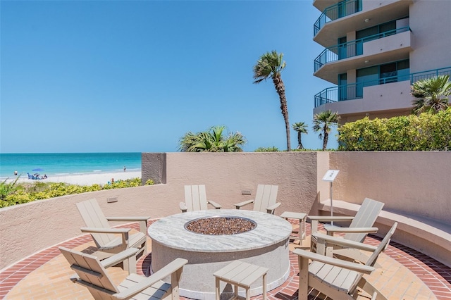 view of patio featuring a water view, a fire pit, and a view of the beach