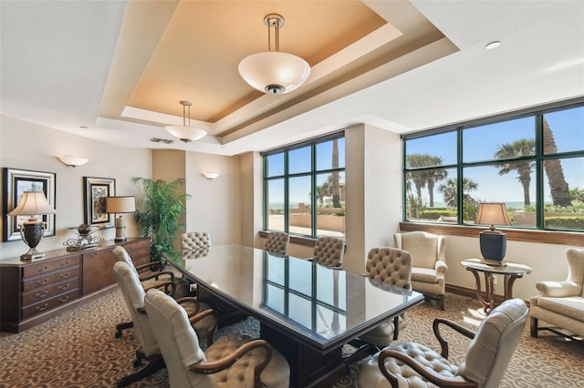 carpeted office space featuring baseboards, visible vents, and a raised ceiling