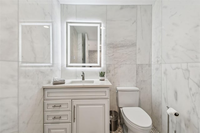 bathroom with tile walls, vanity, and toilet