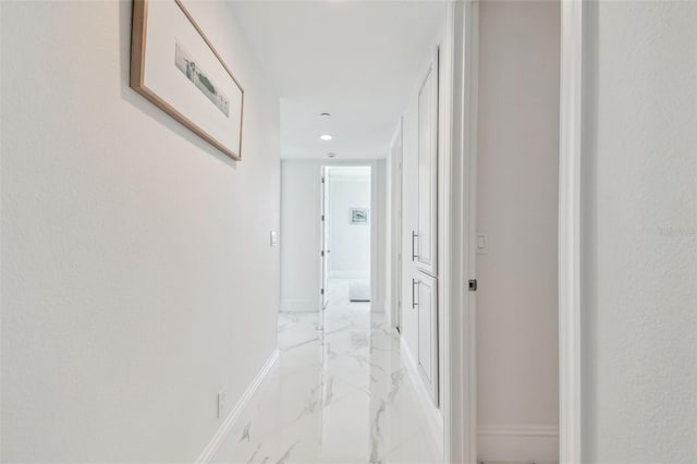 hallway with baseboards, recessed lighting, and marble finish floor